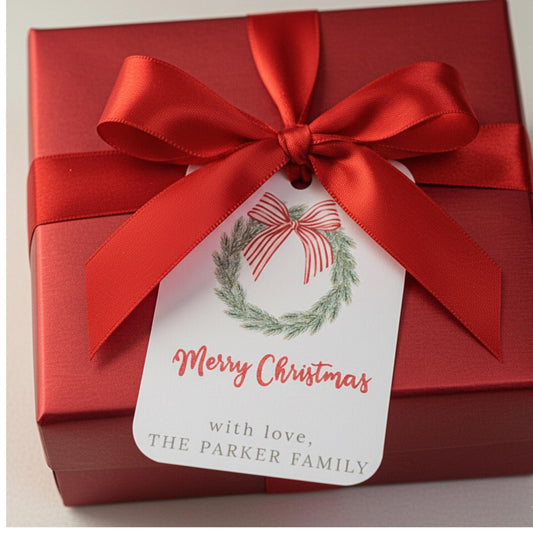 A red gift box tied with a large red satin bow and a white Christmas tag that reads 'Merry Christmas with love, THE PARKER FAMILY.'.