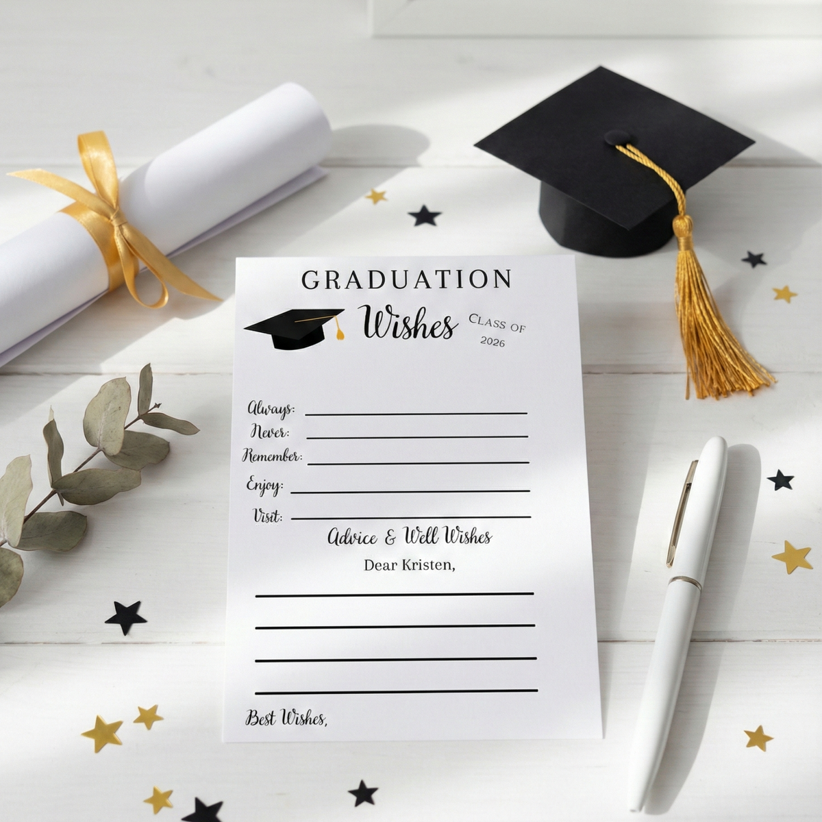 A graduation-themed printed card on a white wooden surface, styled with a black graduation cap and tassel, a rolled diploma with a gold ribbon, a white pen, and scattered gold and black star confetti. The card reads 'Graduation Wishes Class of 2026' with lines for personal details.