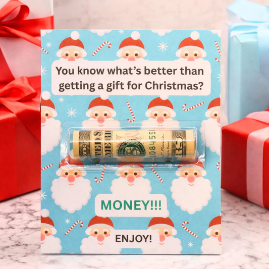 A Christmas-themed money roll gift card featuring a light blue background with a repeating Santa Claus pattern. The card has a clear plastic window showing a rolled dollar bill inside, with text that reads 'You know what's better than getting a gift for Christmas?' and 'MONEY!!! ENJOY!'.