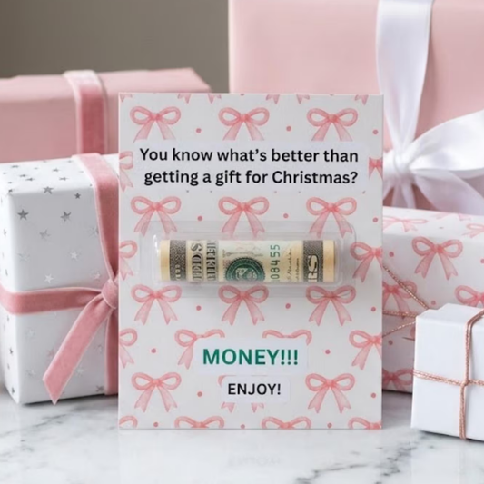 A Christmas themed money holder card that is white with pink bows all over it that reads "You know what's better than getting a gift for Christmas? MONEY! ENJOY! There is a plastic money holder tube in the middle of the card for rolled up bills or a check for gifting.