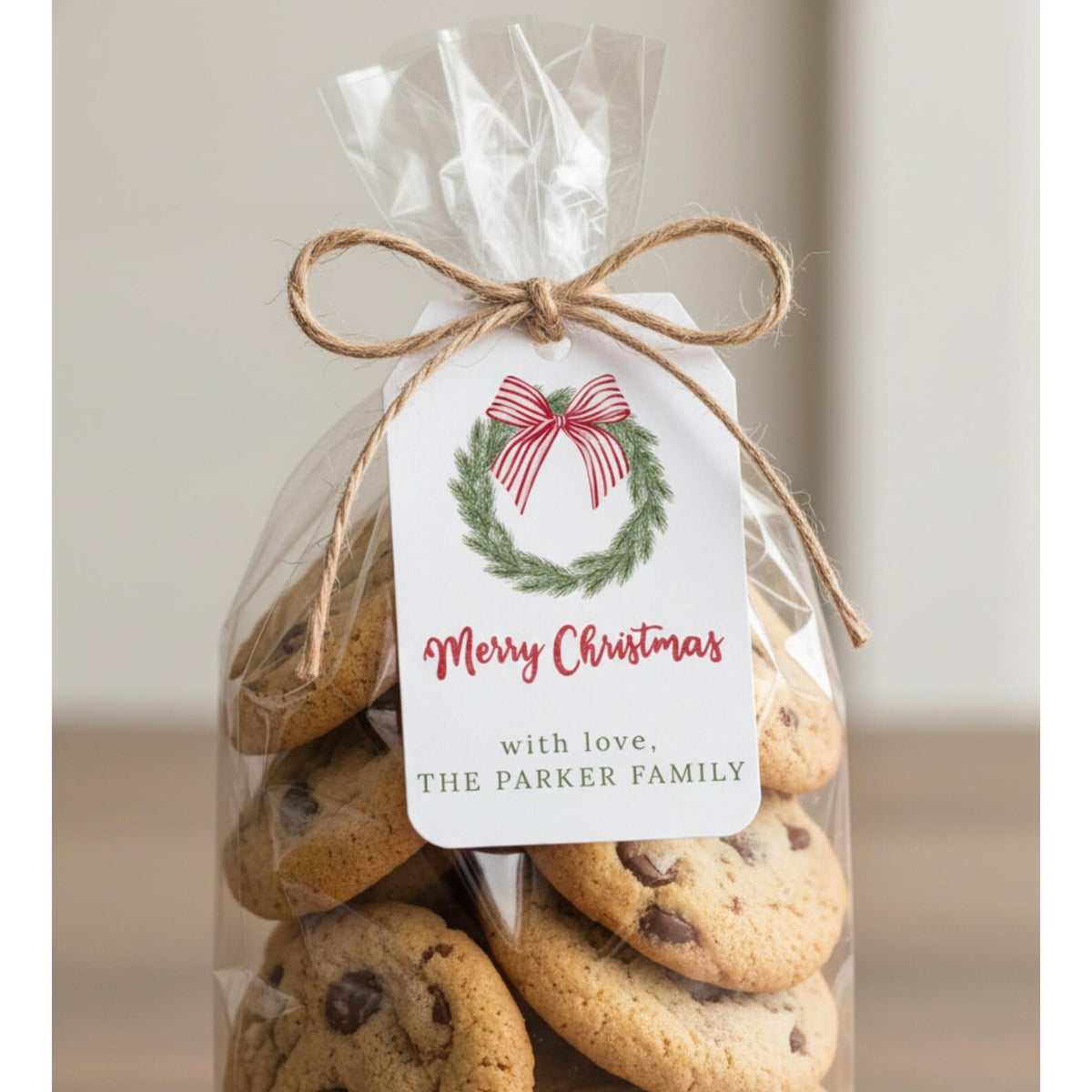 A bag of chocolate chip cookies tied with a twine bow and labeled with a white Christmas tag that reads 'Merry Christmas with love, THE PARKER FAMILY'.